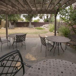 A covered patio with metal tables and chairs in a backyard setting.