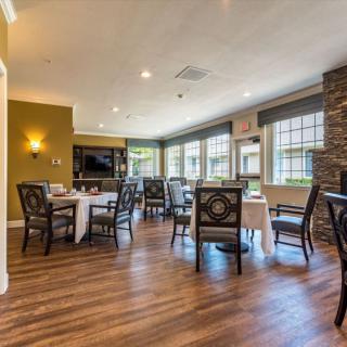 A cozy dining area with wooden flooring and large windows providing natural light.