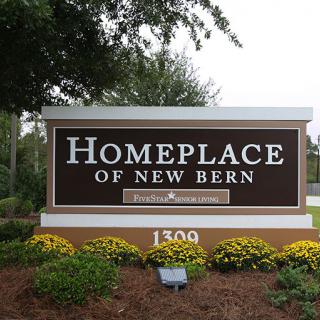 Entrance sign for Homeplace of New Bern surrounded by flowers.