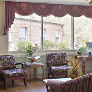 A comfortable living room with patterned chairs, a large window, and elegant curtains.