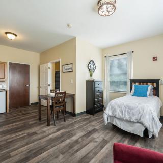 A cozy bedroom with a single bed, desk, and wooden flooring.