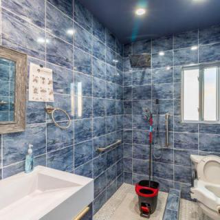 A modern bathroom with blue tiled walls, featuring a sink, mirror, and toilet.