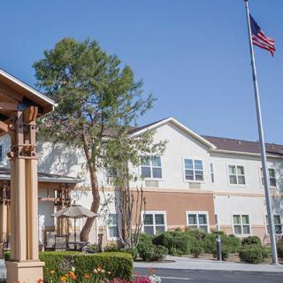 A residential building with a flagpole and trees in an outdoor setting.
