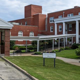 A view of a brick hospital building showcasing a landscaped entrance.