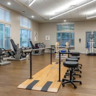 A spacious physical therapy room equipped with exercise machines and parallel bars for rehabilitation.