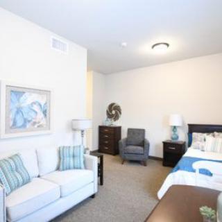 A cozy bedroom featuring a sofa, bed, armchair, and decorative elements.