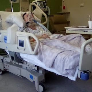 A patient recovering in a hospital bed, surrounded by medical equipment.