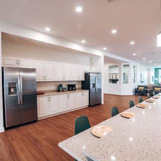 A spacious modern kitchen featuring white cabinets, stainless steel appliances, and a large island countertop.