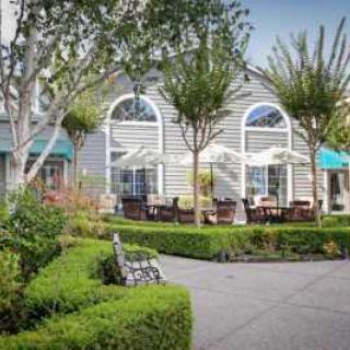A charming house with an inviting garden and outdoor seating area on a sunny day.