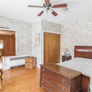 A traditional bedroom with wooden furniture and a ceiling fan, featuring patterned wallpaper.