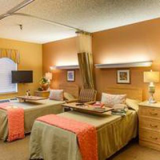 A hospital room with two patient beds, each equipped with bedside tables and a television, creating a comfortable healthcare environment.