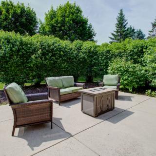 A cozy outdoor patio with comfortable seating surrounded by lush greenery.