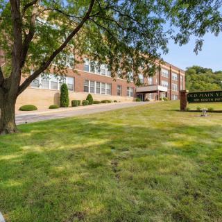 A sunny view of a school building with a lawn and trees.