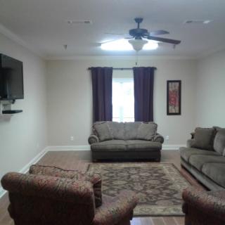 A cozy living room with sofas, armchairs, a TV, and a rug.