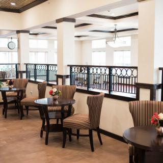 A cozy dining area with elegantly arranged tables and chairs, featuring warm lighting and tasteful decor.