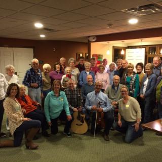 A large group of people gathered indoors, smiling for a group photo.