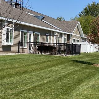 A backyard view of a house with a well-maintained lawn and patio area.