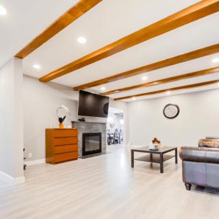 A modern and cozy living room featuring exposed wood beams, a fireplace, and minimalist decor.