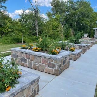 A beautifully landscaped garden with stone planters and a walkway surrounded by greenery.