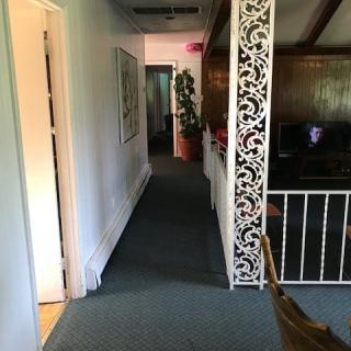 A hallway in an office space with a carpeted floor, decorative paneling, and a railing.