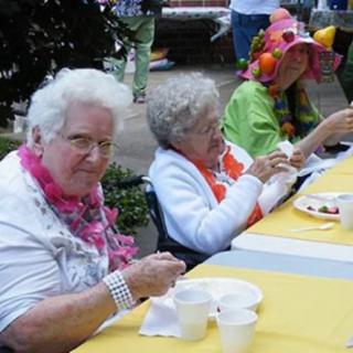 Elderly individuals enjoying a festive outdoor gathering with food.