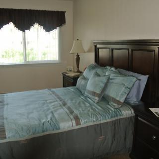 A neatly arranged bedroom with a bed, lamp, and window.