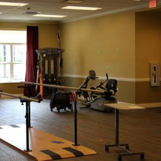 A spacious rehabilitation area with exercise equipment, including a parallel bar for physical therapy.