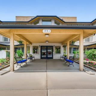 The entrance of a modern building with benches and landscaped surroundings.