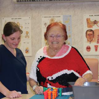 A joyful moment shared between a therapist and an elderly woman during a therapy session.