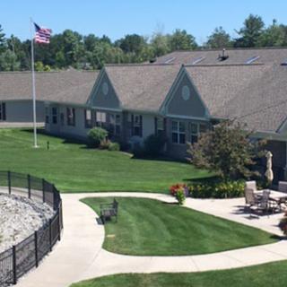A sunny day at a well-maintained residential facility with landscaped gardens and a flag flying.