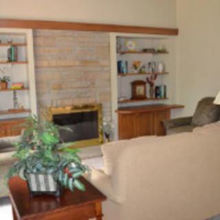 A cozy living room featuring a fireplace, surrounded by built-in shelves and comfortable furniture.