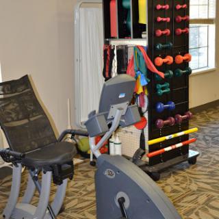 A well-equipped fitness area featuring a recumbent bike and various weight training equipment.