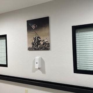 A framed black and white photograph depicting a historic military moment, displayed on a wall with windows.