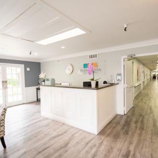 A bright and modern reception area with a sleek desk and long corridor.