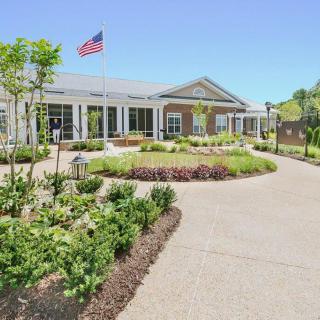 A beautifully landscaped pathway leading to a building with an American flag flying overhead.