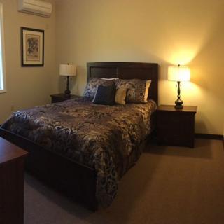 A cozy bedroom with a comfortable bed, nightstands, and warm lighting.
