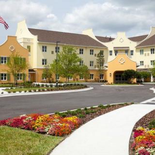 A well-maintained building with a landscaped entrance featuring vibrant flowers and an American flag.