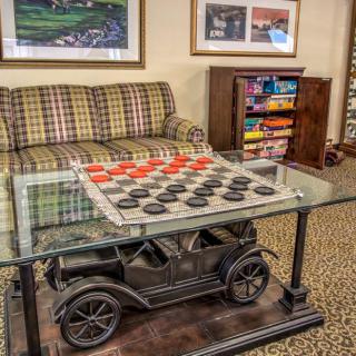 A cozy living room featuring a unique coffee table designed like a vintage car, with a checkers game set up on top.