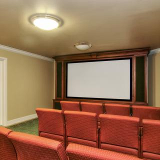 A cozy home theater with rows of comfortable seating and a large projection screen.