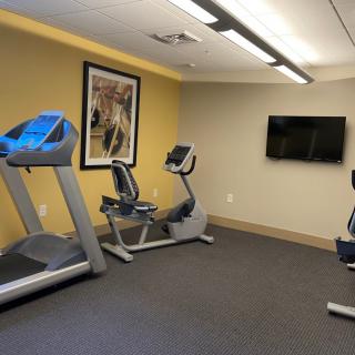 A small gym with a treadmill, exercise bikes, and a TV.