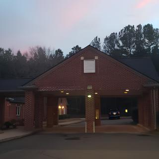 A brick building with a drive-through area illuminated in the evening light.