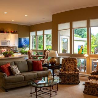 A cozy and well-lit living room with modern furniture and large windows that bring in natural light.