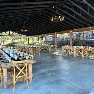 A beautifully designed outdoor dining area, featuring wooden tables and chandeliers, perfect for events.
