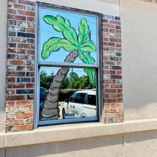 A vibrant mural of a palm tree painted on a window, adding a tropical touch to the building's exterior.