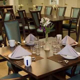 A neatly set dining table with folded napkins and floral arrangement.