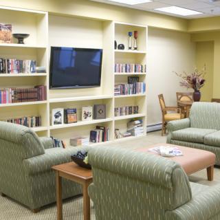 A cozy living room with a large bookshelf, comfortable seating, and a television.