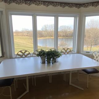 A white dining table set in a bright room overlooking a scenic outdoor view.