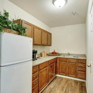 A cozy kitchen with wooden cabinets, a white refrigerator, and modern lighting.