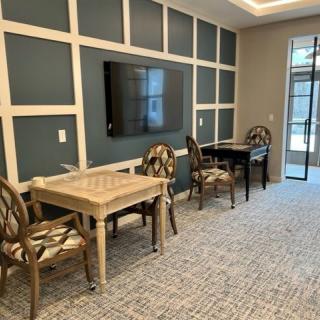 A modern conference room with tables, chairs, and a wall-mounted television.