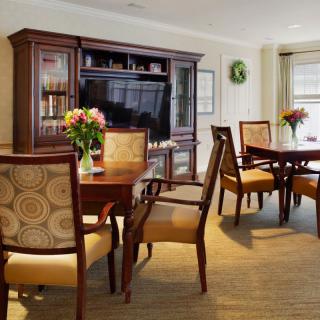 A cozy dining room with a wooden dining set and a television in the background.